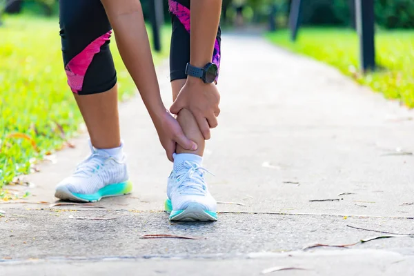 Mujer joven sosteniendo el tobillo con dolor en la pista del estadio. Roto t — Foto de Stock