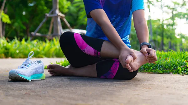 Mujer joven sosteniendo el tobillo con dolor en la pista del estadio. Roto t — Foto de Stock