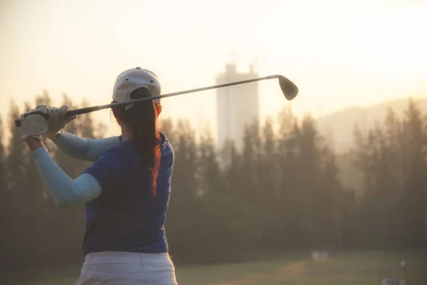 女性のゴルファーやアジアの女性のゴルフ選手は 緑の夕日の夜の時間にゴルフスイングティーオフを行う 彼女はおそらく運動を行う — ストック写真