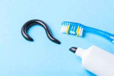 Siyah beyaz dişler için kömür gelen diş macunu. Soru işareti, tüp ve mavi arka plan üzerinde diş fırçası şeklinde sabunlar. Kavramı seçmek için hangi diş macunu? 