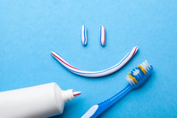 Pasty do zębów w postaci twarz z uśmiechem. Tubki pasty do zębów i szczoteczkę do zębów na niebieskim tle. Odświeżanie i pasty do zębów. — Zdjęcie stockowe