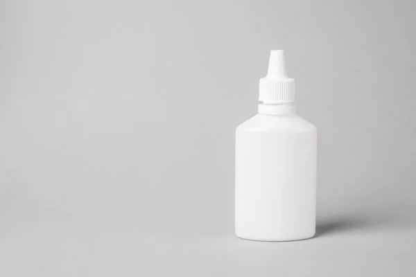 Pulverizar para o nariz em uma garrafa de plástico branco em um fundo cinza. Aerosol do resfriado comum ou alergia. mock-up — Fotografia de Stock