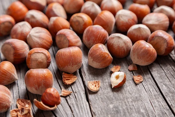 Yığın Hazel ve iki fındık ile eski bir ahşap masa üzerinde kırık deniz hayvanı kabuğu.