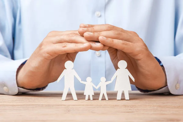 Ιατρική ή ταξιδιωτική ασφάλιση. Ο άνθρωπος καλύπτει την οικογένεια με τα χέρια του από τον πατέρα, μητέρα, γιος και κόρη — Φωτογραφία Αρχείου