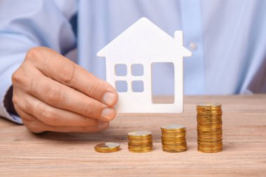 Satış veya satın house. Paralar kazık ve evi adam sembolü tutar