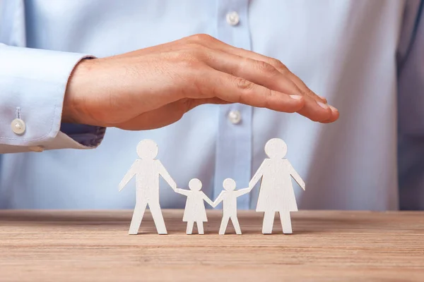 Seguro médico o de viaje. El hombre cubre la familia con sus manos de su padre, madre, hijo e hija — Foto de Stock