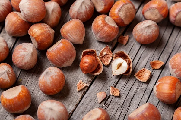 Yığın Hazel ve iki fındık ile eski bir ahşap masa üzerinde kırık deniz hayvanı kabuğu