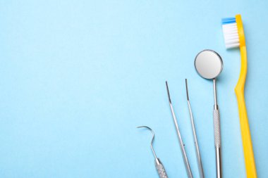 Diş aletleri. Diş Ayna, sonda kanca, cımbız ve mavi arka plan üzerinde diş fırçası