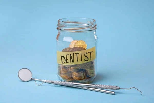 Expensive dental services. Glass jar with coins and dental instruments, mirror and probe hooks — Stock Photo, Image