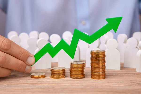 La flecha del gráfico es hacia arriba sosteniendo hombre y pila de monedas escaleras. Crecimiento de las ventas, beneficios e inversiones —  Fotos de Stock