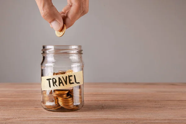 Viaggia. Vaso di vetro con monete e un'iscrizione di viaggio. L'uomo tiene la moneta in mano — Foto Stock