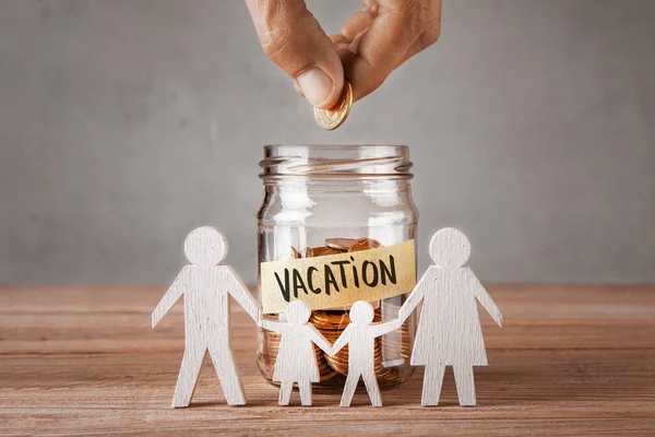 Vacation. Glass jar with coins and an inscription is vacation and symbol of  family with children. The man holds  coin in his hand — Stock Photo, Image