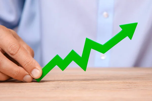 Crecimiento en ventas y ganancias. Flecha verde apuntando hacia las manos del hombre — Foto de Stock