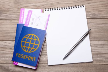 Pasaport ile uçak ve ahşap masa üzerinde kalemle dizüstü için iki bilet. mock-up