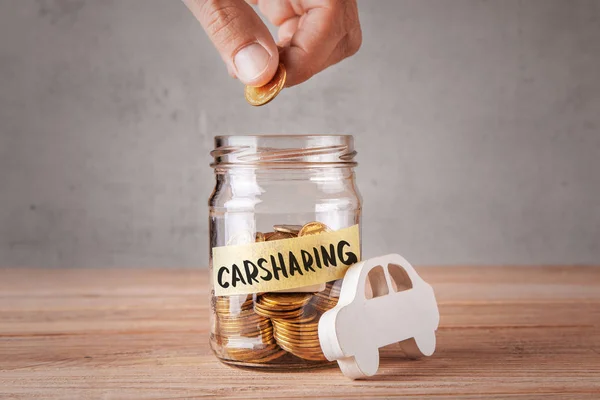 Carsharing. Glass jar with coins and an inscription of carsharing and symbol of  car. Man holds coin