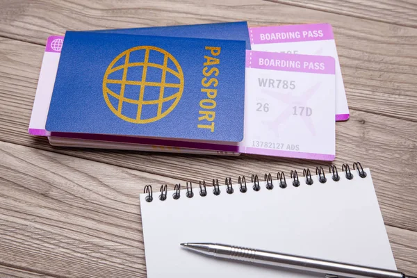 Pasaport ile uçak ve ahşap masa üzerinde kalemle dizüstü için iki bilet. — Stok fotoğraf