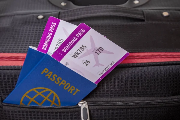 Maleta Negra y dos billetes para avión con pasaportes están asomándose de sus bolsillos —  Fotos de Stock