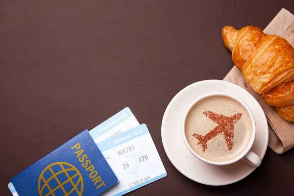 Cup of coffee with an airplane on the foam. I like to break coffee with croissant in flight. Paspor and ticket with smrtrfonom — Stock Photo, Image