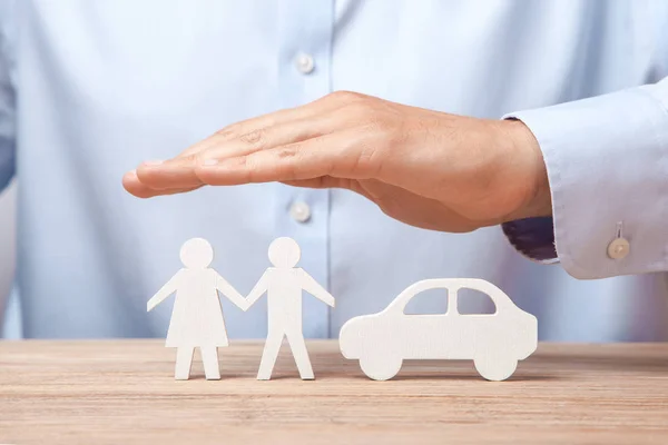 Försäkring av ung familj och bil. Mannen i skjorta täcker händerna med familj av man och kvinna och bil — Stockfoto