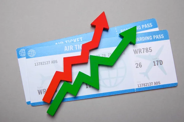 Two airplane tickets and red and green arrow up. Increase in sales of air tickets in season