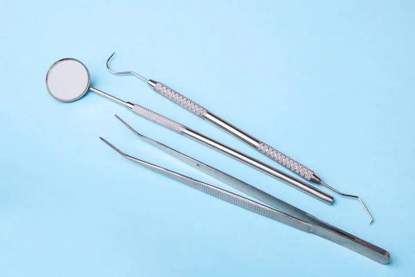 Dental instruments. Dental mirror, probe hook, tweezers on blue