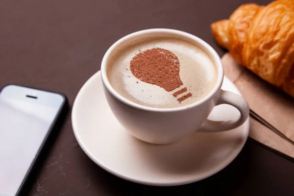 Fincan kahve bir ampul fikri üzerine köpük ile. Kahve yeni fikirleri ve yaratıcılığı verir. Sabah kahvesi — Stok fotoğraf