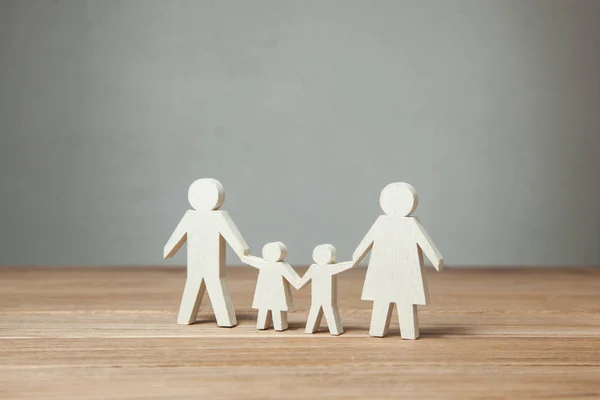 Símbolo familiar, padre, madre, hija e hijo tomados de la mano en la mesa de madera — Foto de Stock