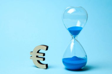 Kum saati ve mavi arka plan üzerinde para euro sembolü. Zaman para demektir
