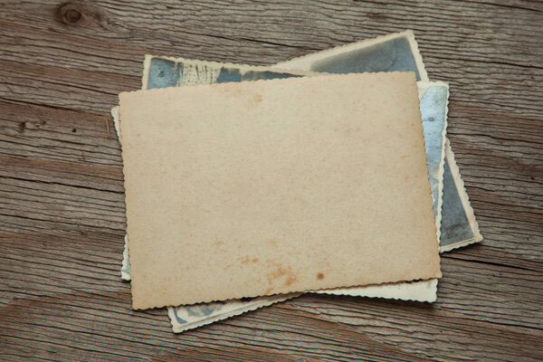 Stack old photos on table. Mock-up blank paper. Postcard rumpled and dirty vintage