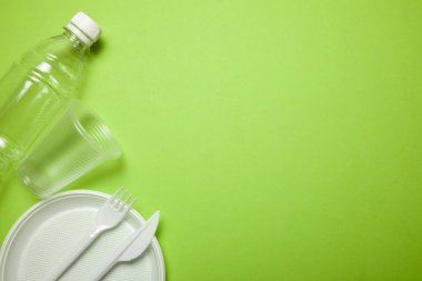 Yeşil plastik tek kullanımlık kaplar. çatal, bıçak, tabak, bardak ve şişe