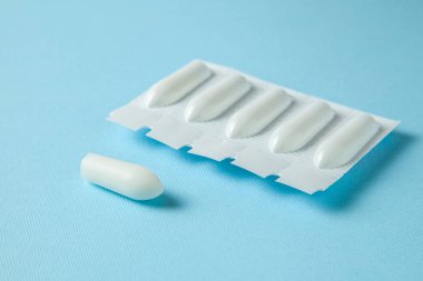 Fitil mavi bir arka plan üzerinde anal veya vajinal kullanım için. Hemoroid, sıcaklık, pamukçuk tedavisi için mumlar