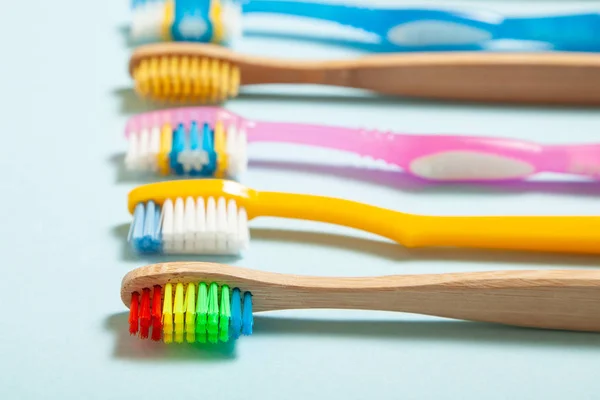 Set di spazzolini da denti su sfondo blu. Concetto selezione spazzolino da denti, bambù eco-friendly e plastica — Foto Stock