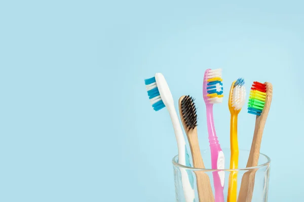 Set di spazzolini da denti in vetro su fondo blu. Concetto selezione spazzolino da denti, bambù eco-friendly e plastica — Foto Stock