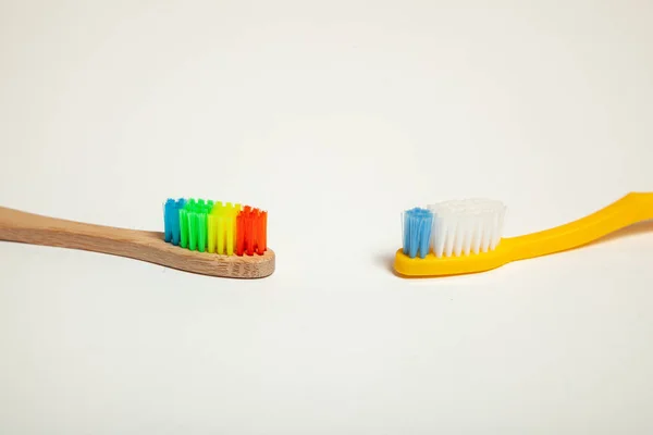 Tannbørster på grå bakgrunn. Konseptvalg av tannbørste, miljøvennlig bambus og plast – stockfoto