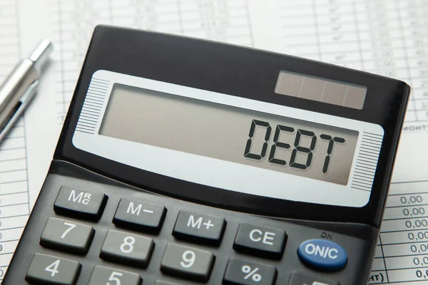 Calculator with the inscription on the DEBT display on the paper tables — Stock Photo, Image