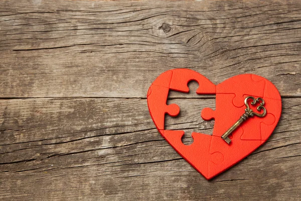 Rött hjärta pussel utan del och en gammal vintage nyckel på trä bakgrund. Öppet hjärta för kärlek, alla hjärtans dag. Kopiera utrymme — Stockfoto