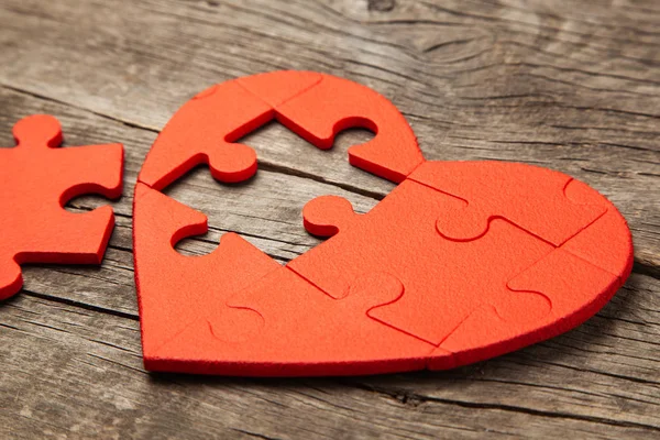 心脏拼图红色的木背景。爱情人节或疾病的心的第二半的概念 — 图库照片