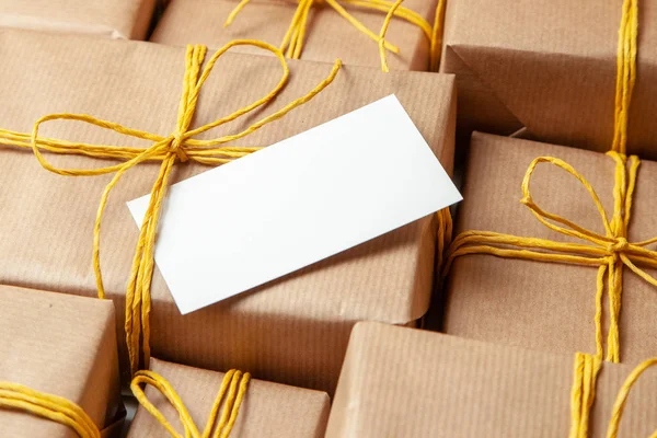 Pile Gift boxes in festive packaging with golden yellow bows and note or card. Delivery of gifts by the postal cargo