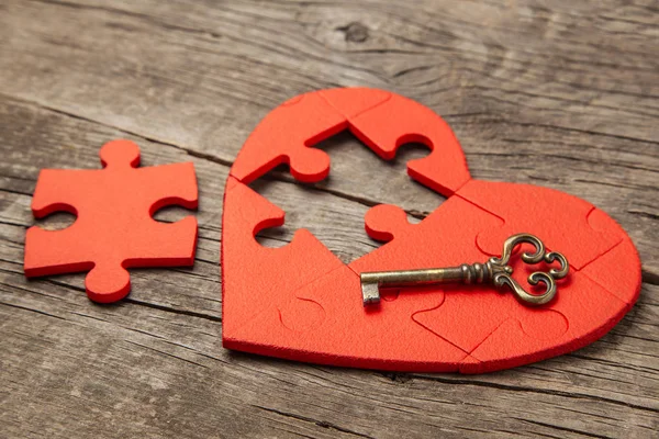 Rött hjärta pussel utan del och en gammal vintage nyckel på trä bakgrund. Öppet hjärta för kärlek, alla hjärtans dag — Stockfoto
