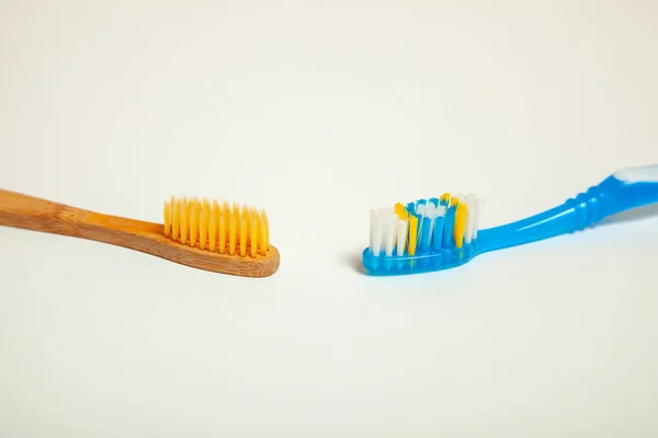 Зубные щетки на сером фоне. Концептуальный выбор зубной щетки, бамбук экологически чистые и пластиковые — стоковое фото