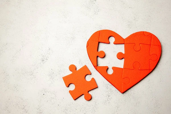 Hart puzzel rood op grijze achtergrond. Tweede helft van het concept van het hart in de liefde voor Valentijnsdag of ziekte. Ruimte voor tekst kopiëren — Stockfoto