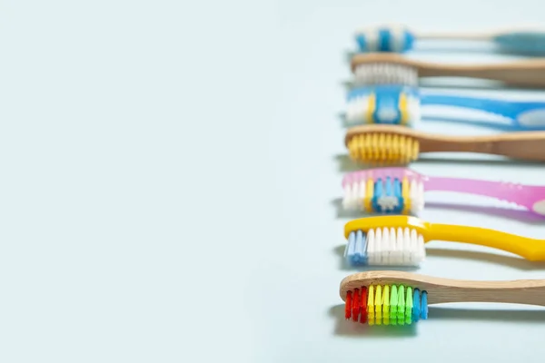 Set di spazzolini da denti su sfondo blu. Concetto selezione spazzolino da denti, bambù eco-friendly e plastica. Copia spazio per testo — Foto Stock