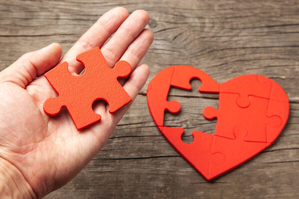 Man holds in his hand part of the puzzle from the heart. How to find your soul mate or work for the soul