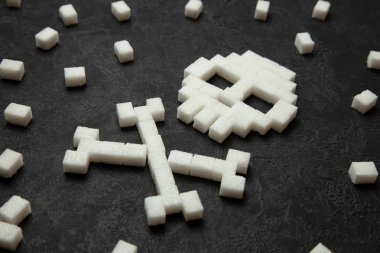 Siyah arka plan üzerinde beyaz şeker küplerini kafatasından. Çok hızlı ulevodov vücut için zararlı ve şeker öldürür. Diyabet