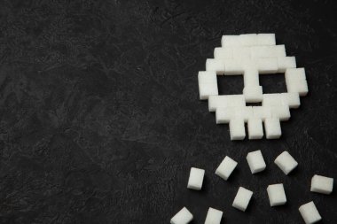 Siyah arka plan üzerinde beyaz şeker küplerini kafatasından. Çok hızlı ulevodov vücut için zararlı ve şeker öldürür. Diyabet ölüme