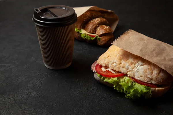 Sandwich and cup of coffee on black background. Morning breakfast or snack when hungry. Street food to go — Stock Photo, Image