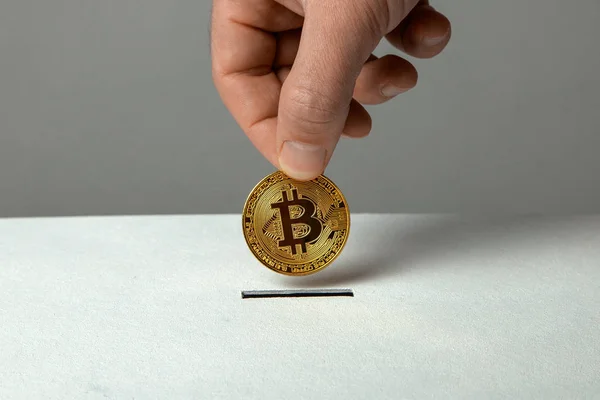 Mann legt Bitcoin mit der Hand ins Sparschwein für Spendenbox — Stockfoto