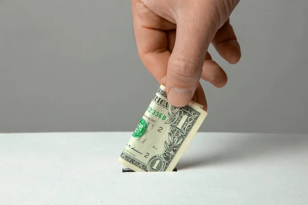 男は、募金箱のスロットにドル札を彼の手を置く. — ストック写真