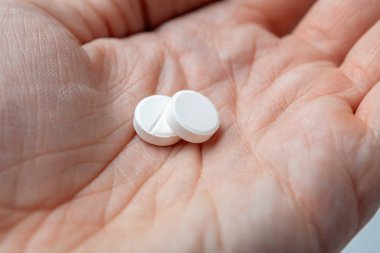 Two white pills in hand. closeup clipart