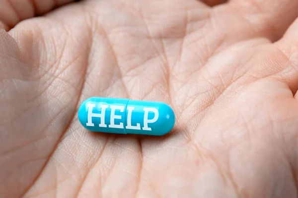 HELP inscription on blue pill capsule in hand. closeup. — Stock Photo, Image